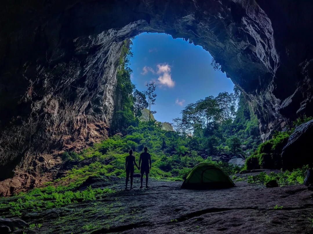 2. Two People Standing at the Entrance of Hang Pygmy Cave, With a Tent Set up in the Cave