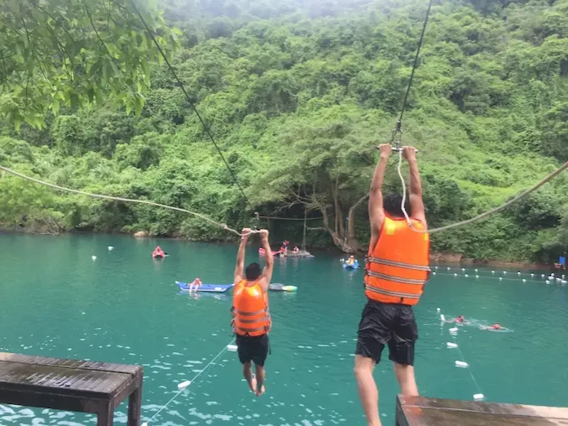 Person on a zipline crossing the Chay River above jungle banks in Phong Nha