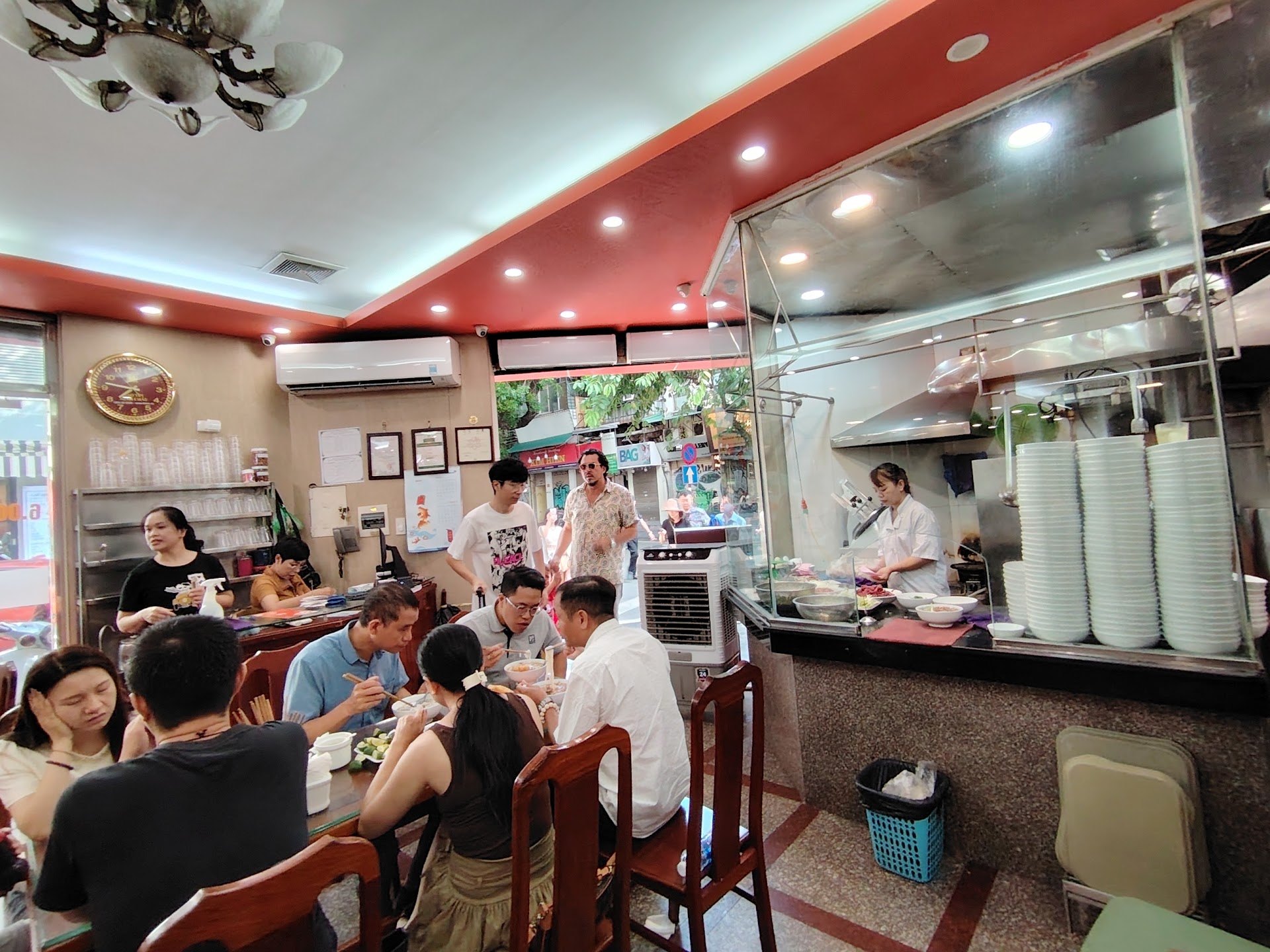 Diners eating beside the glass-fronted kitchen inside Pho 10 Ly Quoc Su