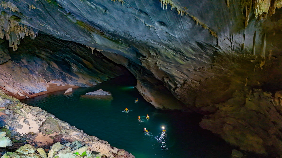 Swimmers crossing the underground river inside Tra Ang cave in Phong Nha