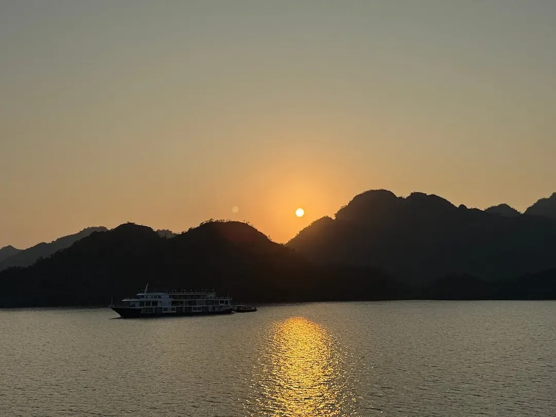 Lan Ha Bay Sunset Cruise With Limestone Mountains Silhouetted and Golden Sunlight Reflecting on Calm Water