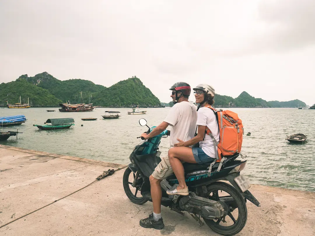 A couple exploring the Cat Ba Island coastline by motorbike as part of their Hanoi to Halong Bay adventure.