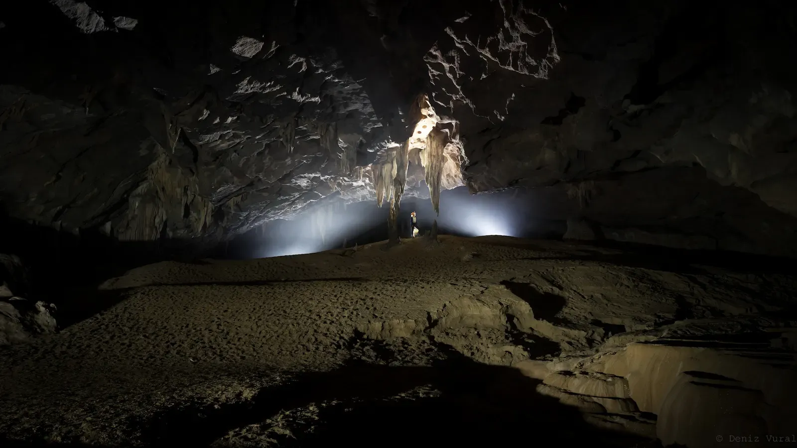 Intricate limestone stalactites hanging from the ceiling of the Nuoc Nut Cave system.