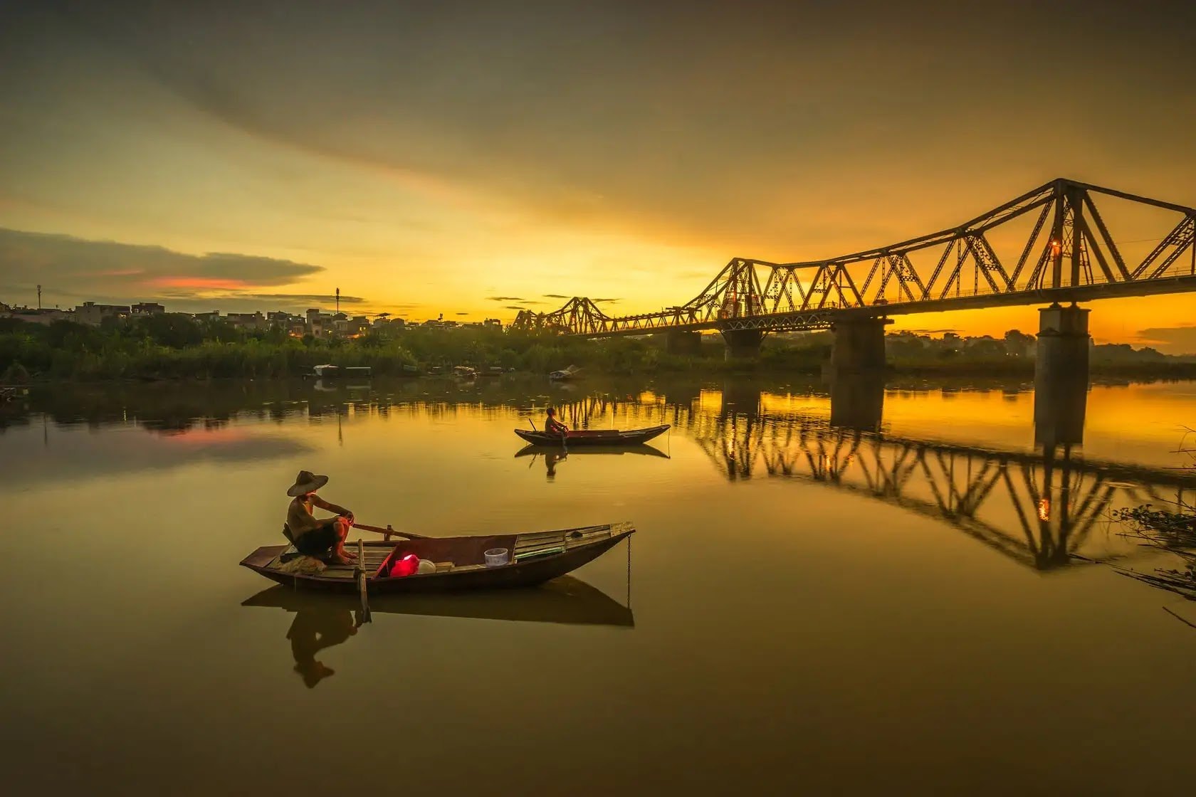 Long Bien Bridge at sunset with two rowing boats on the Red River