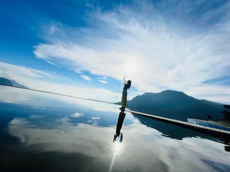 Visitor Standing on the Edge of a Mirror Like Infinity Pool Reflecting Sky and Mountains at a Sapa Viewpoint Near Rong May