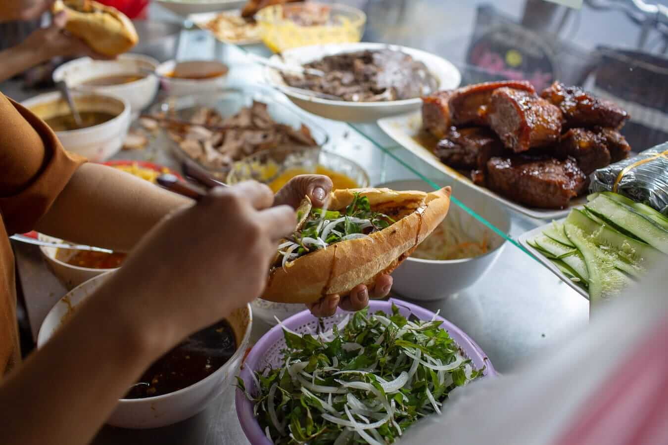 Vendor ladling broth into a bowl at a Vietnamese street food stall