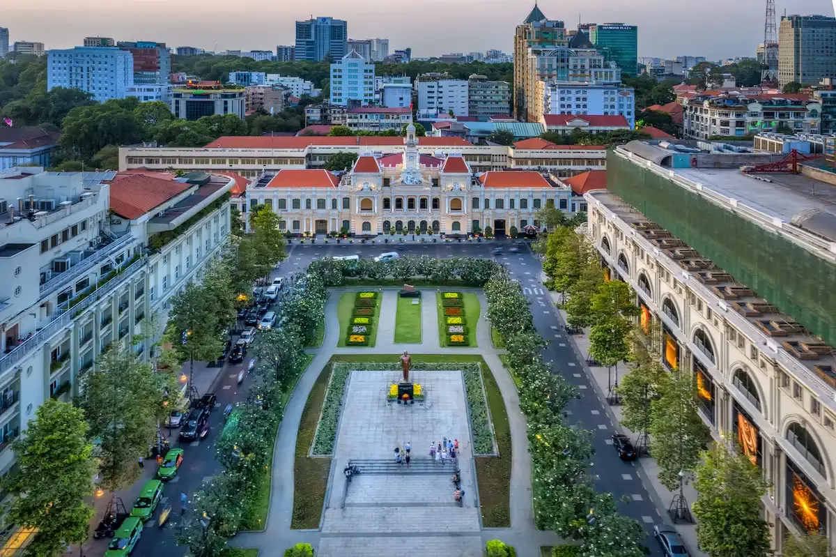 High angle daytime view of Nguyen Hue Walking Street and the People's Committee Building surrounded by city greenery and skyscrapers.