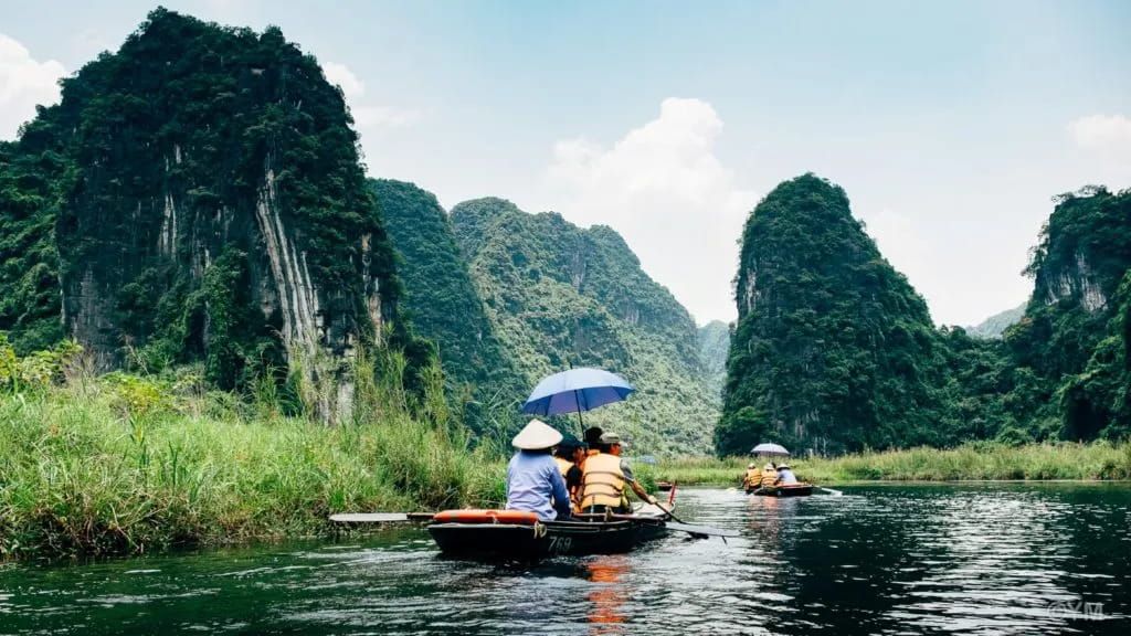 Tourists on Boats Navigating Through the River Surrounded by Limestone Mountains in Tam Coc.