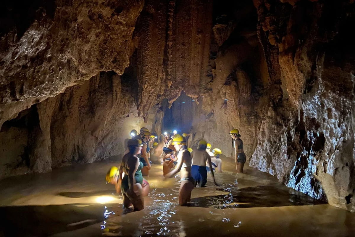 Group wading through a water-filled cave passage by headlamp in Phong Nha