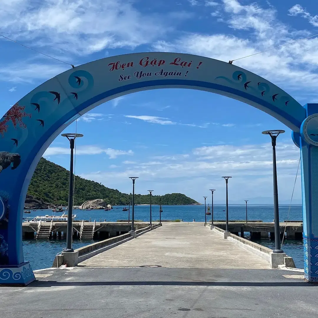 Blue welcome arch at Cham Island pier with See You Again text and ocean view