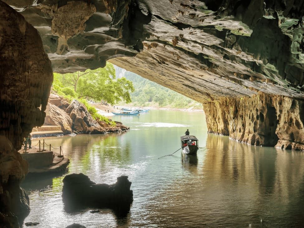 4. a Small Boat Entering the Dark and Majestic Mouth of Phong Nha Cave From the River.