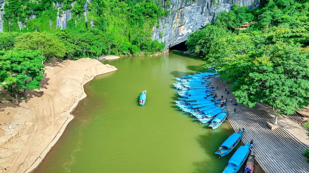 Aerial view of rows of blue tour boats docked on the Son River leading to the cave entrance at Phong Nha-Ke Bang National Park, Vietnam