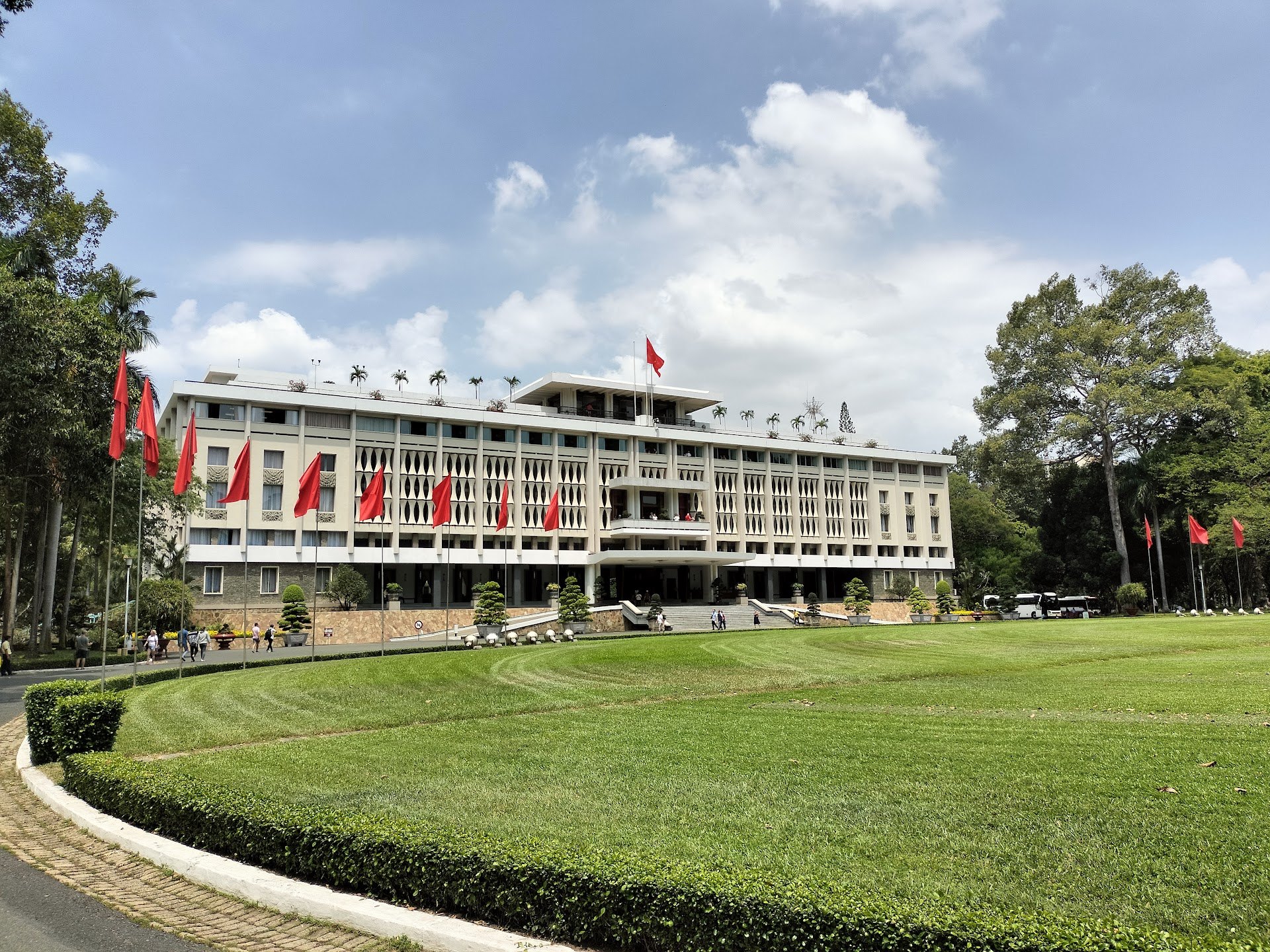 Independence Palace facade and red flags beyond a green lawn in Saigon