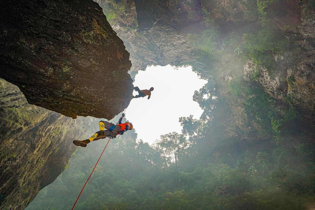 Caver ascending a rope on prussik loops inside a shaft in Phong Nha