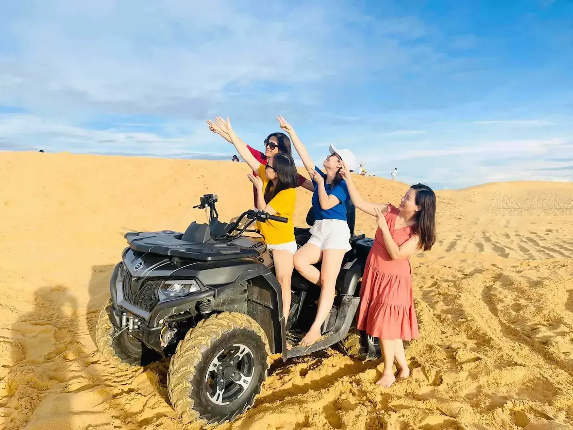 bốn cô gái chụp ảnh bên xe địa hình ở đồi cát quang phú