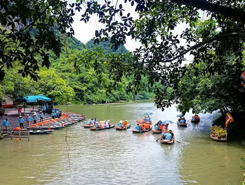 Trang An boat departure dock with multiple wooden boats and limestone karst mountains