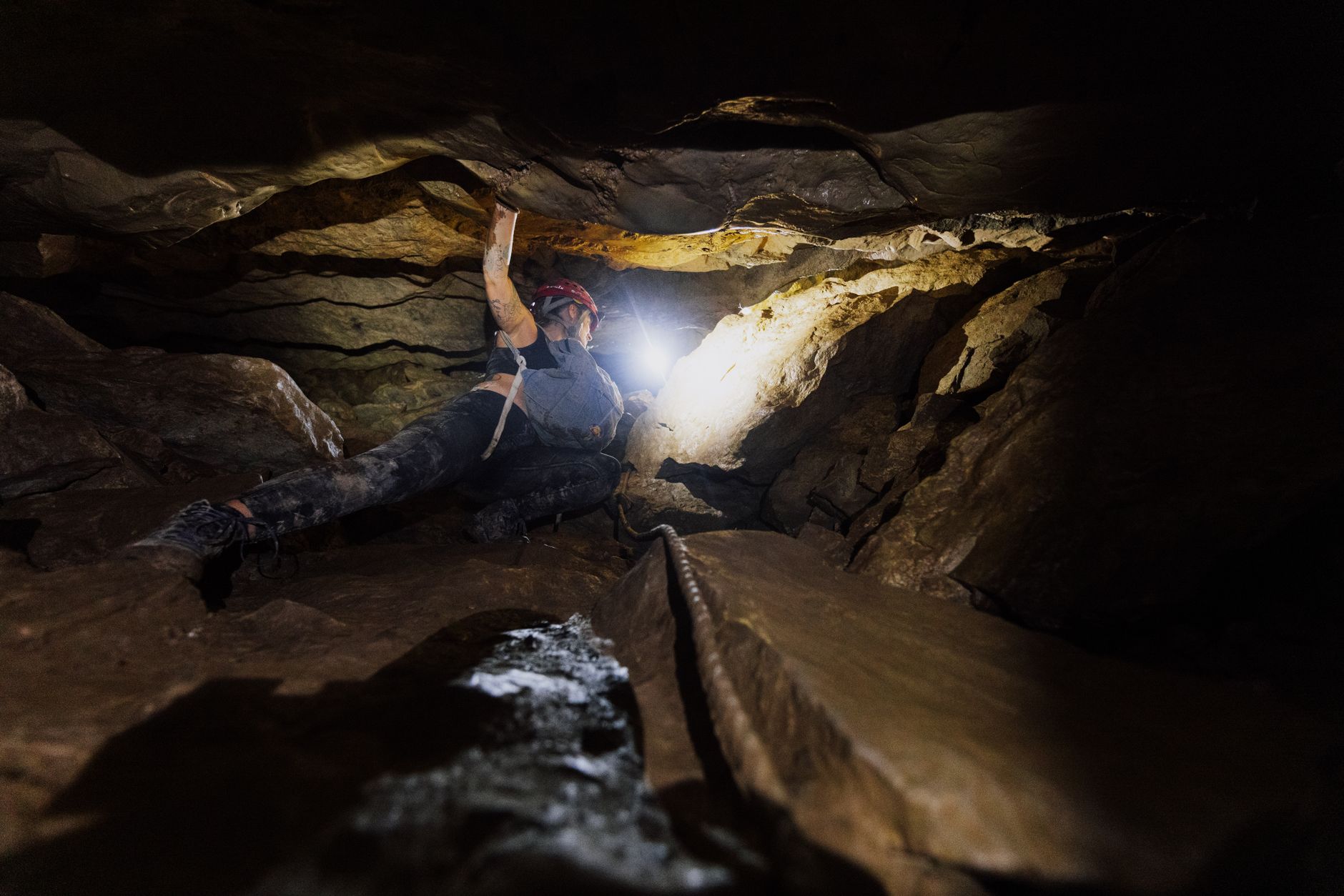 A caver alone in a vast dark chamber lit by head torch
