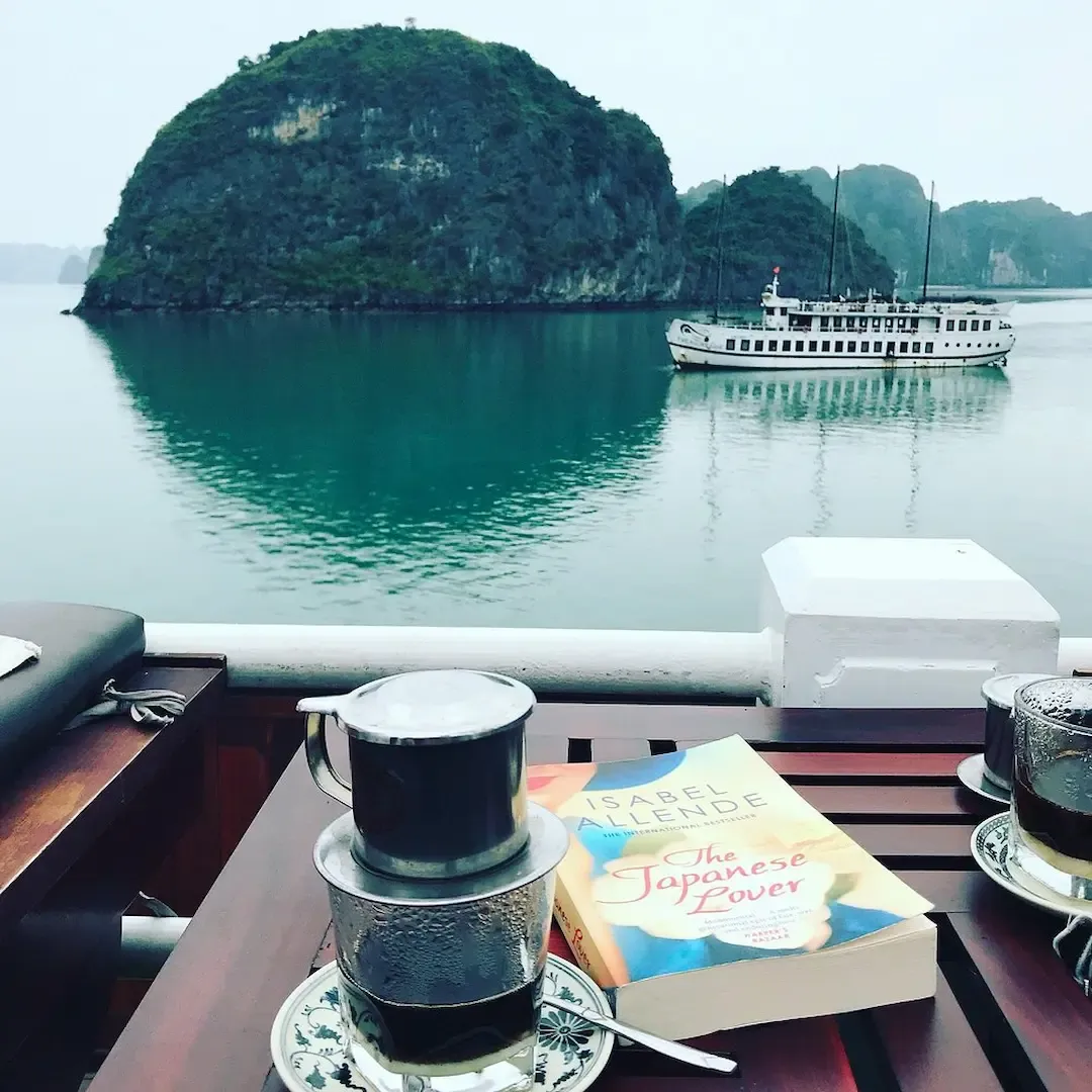 Luxury Cruise Ship Anchored in Pristine Turquoise Waters of Bai Tu Long Bay Surrounded by Dramatic Limestone Island Formations and Clear Skies