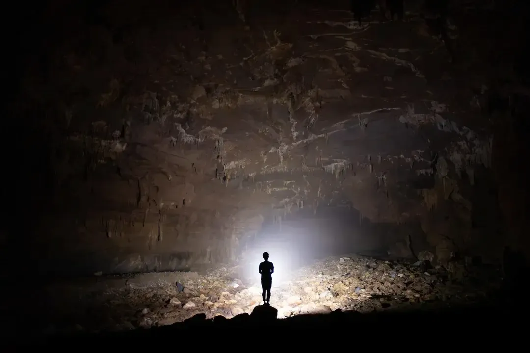 Trekker silhouette in a massive limestone chamber during a Nuoc Nut Cave tour in Phong Nha.