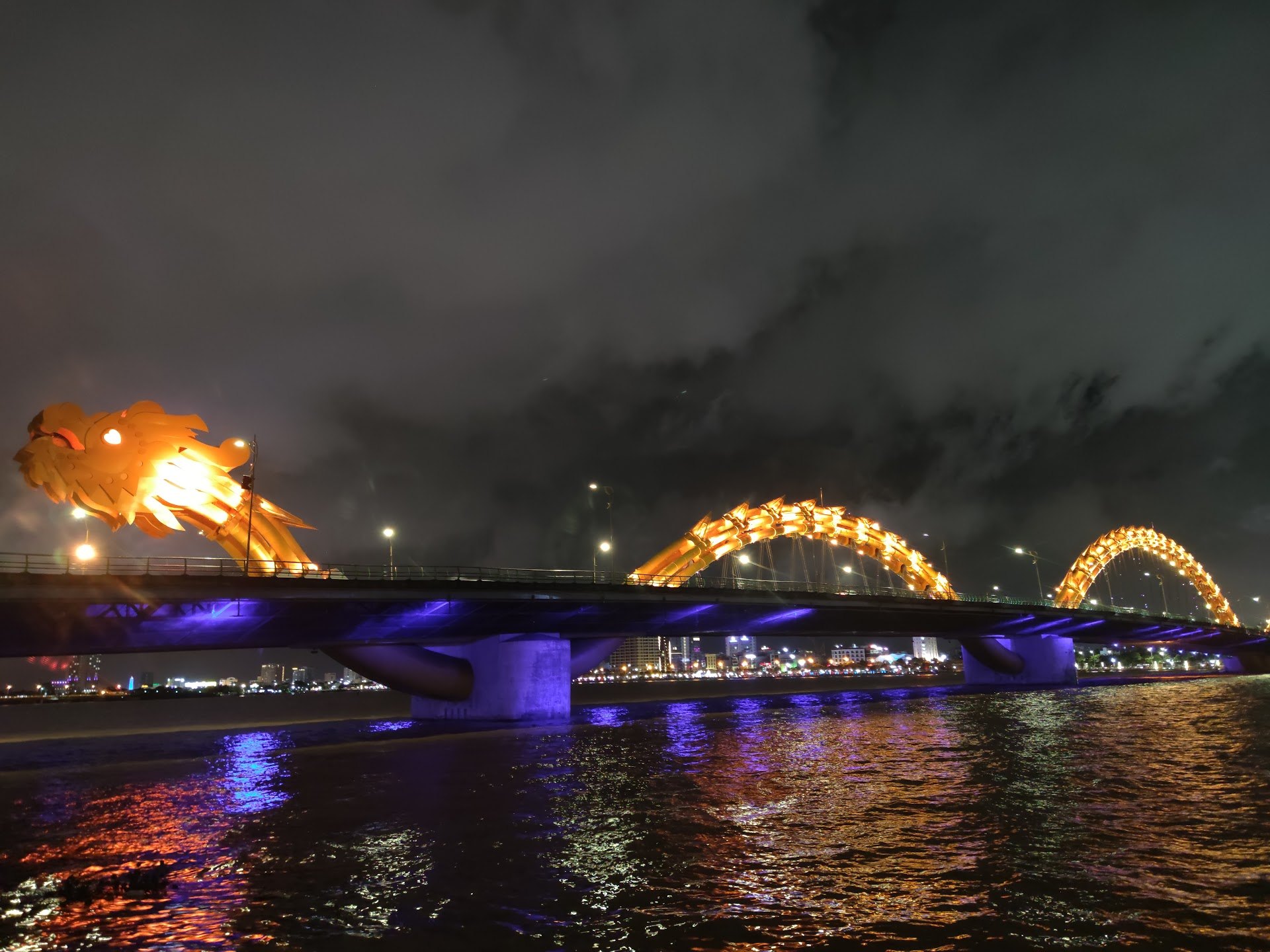 Dragon Bridge lit gold at night over the Han river in Da Nang