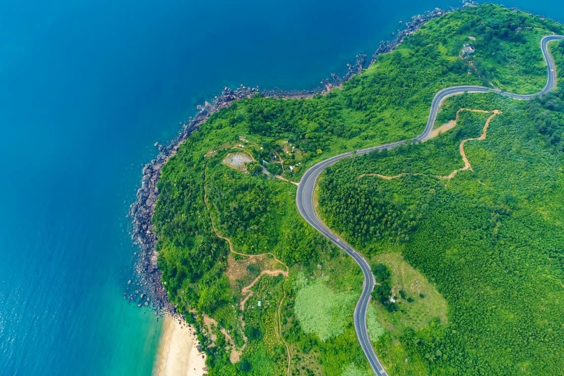 4. Winding Coastal Road Surrounded by Lush Greenery and Blue Ocean Showing Hai Van Pass