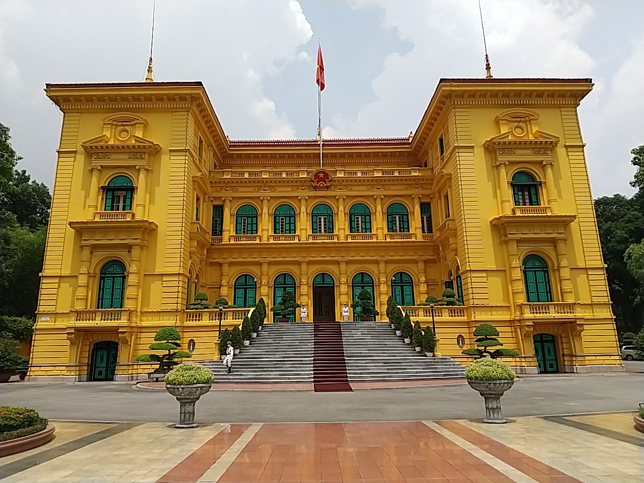 The yellow colonial Presidential Palace in Hanoi seen across its paved forecourt