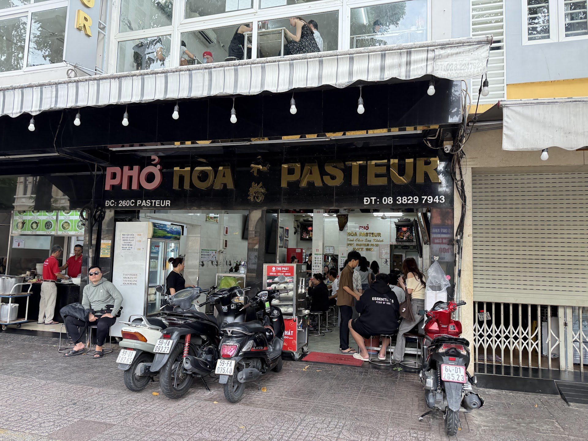 Pho Hoa Pasteur shopfront with customers and parked motorbikes in Saigon