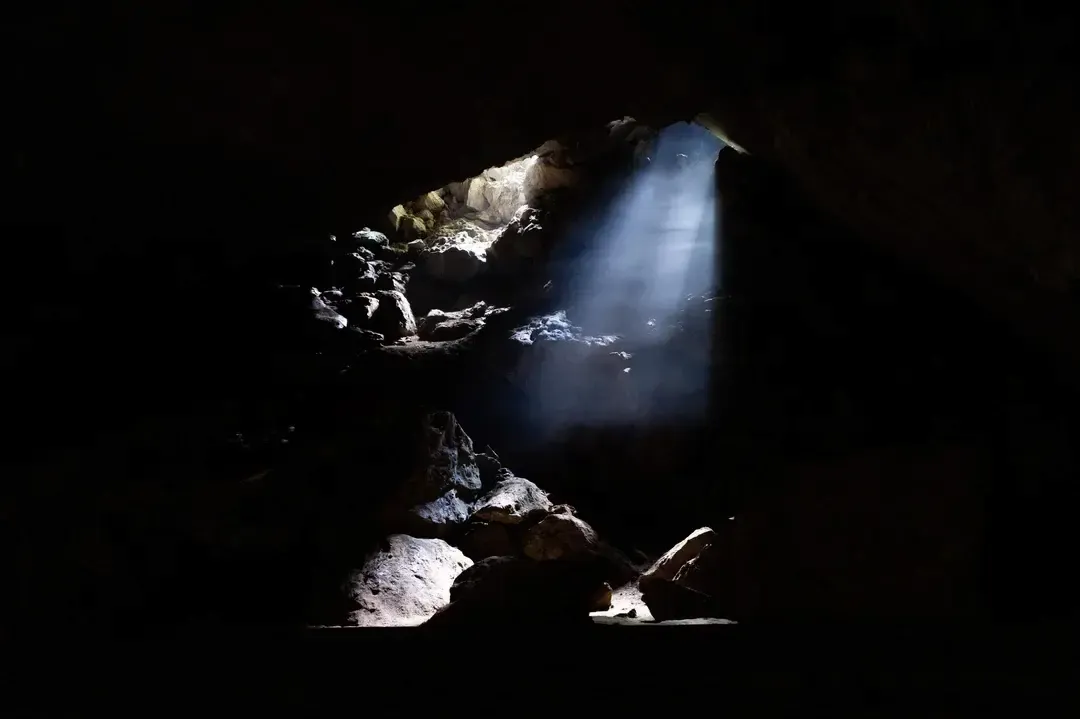 Dramatic sunbeams filtering through the ceiling of Nuoc Nut Cave entrance in Vietnam.