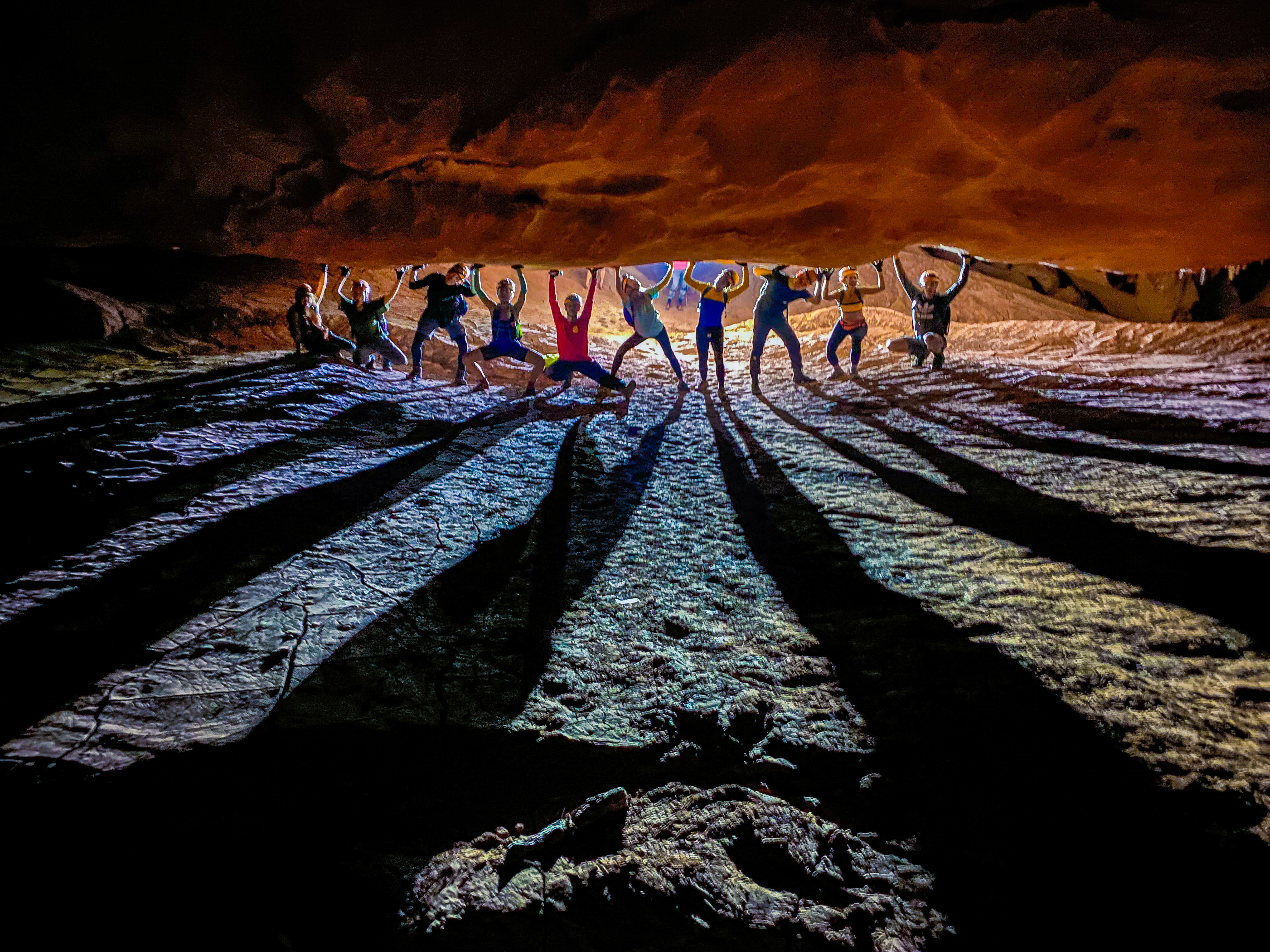 Expedition group silhouetted with long shadows across a cave floor