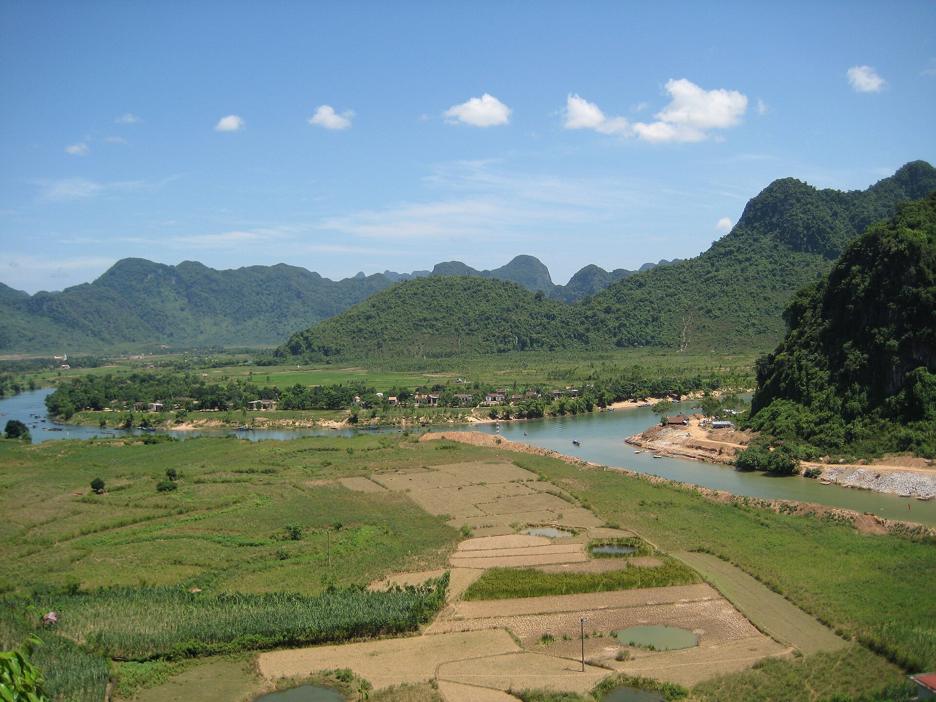 River winding beside fields and limestone hills in the Phong Nha area
