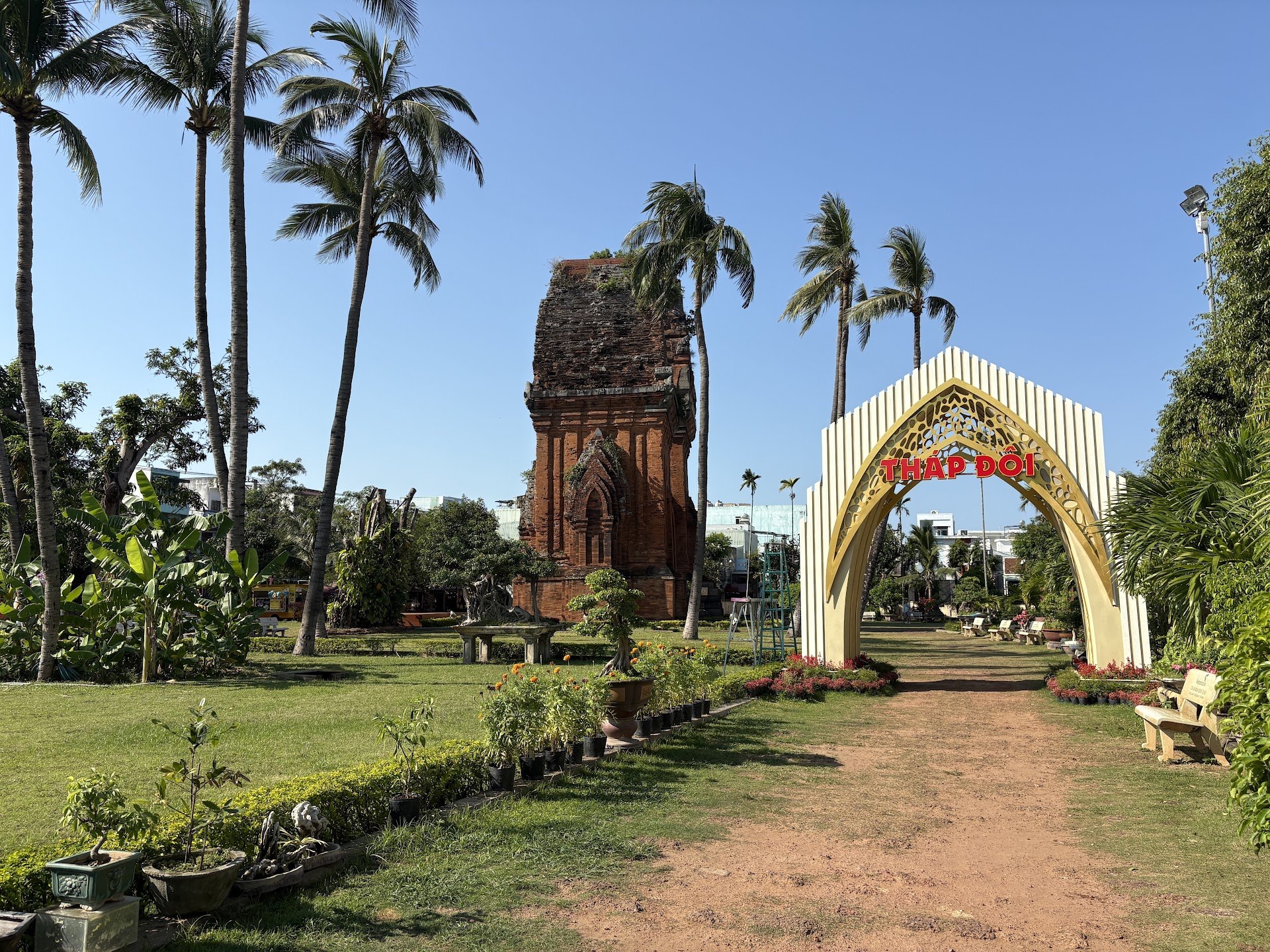 A Cham brick tower among palm trees in the Thap Doi park in Quy Nhon, with an entrance arch