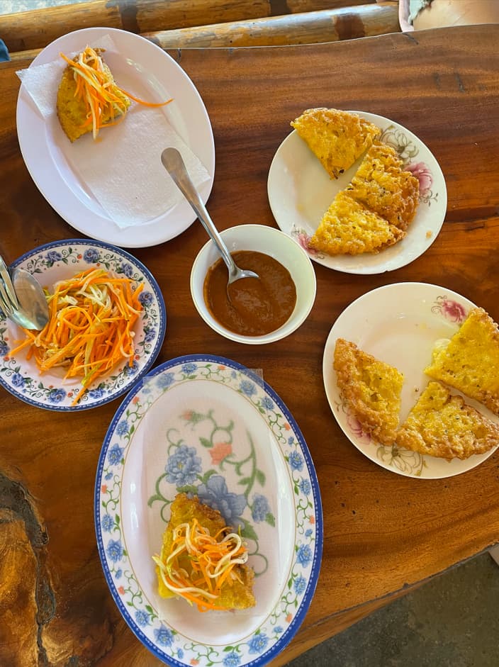 Vietnamesisches Essen mit Kraeutern und Dip auf einem gekachelten Tisch