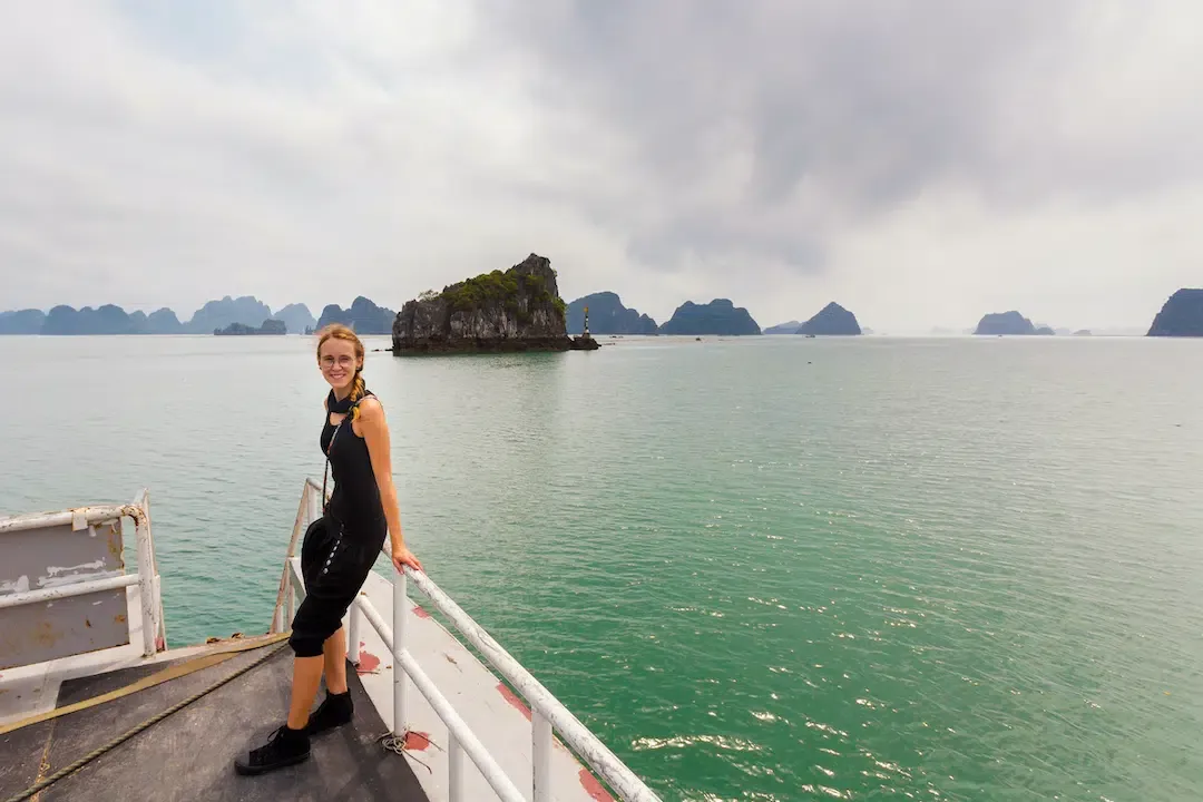A traveler enjoying the limestone island views in Bai Tu Long Bay during a peaceful Hanoi to Halong Bay cruise.