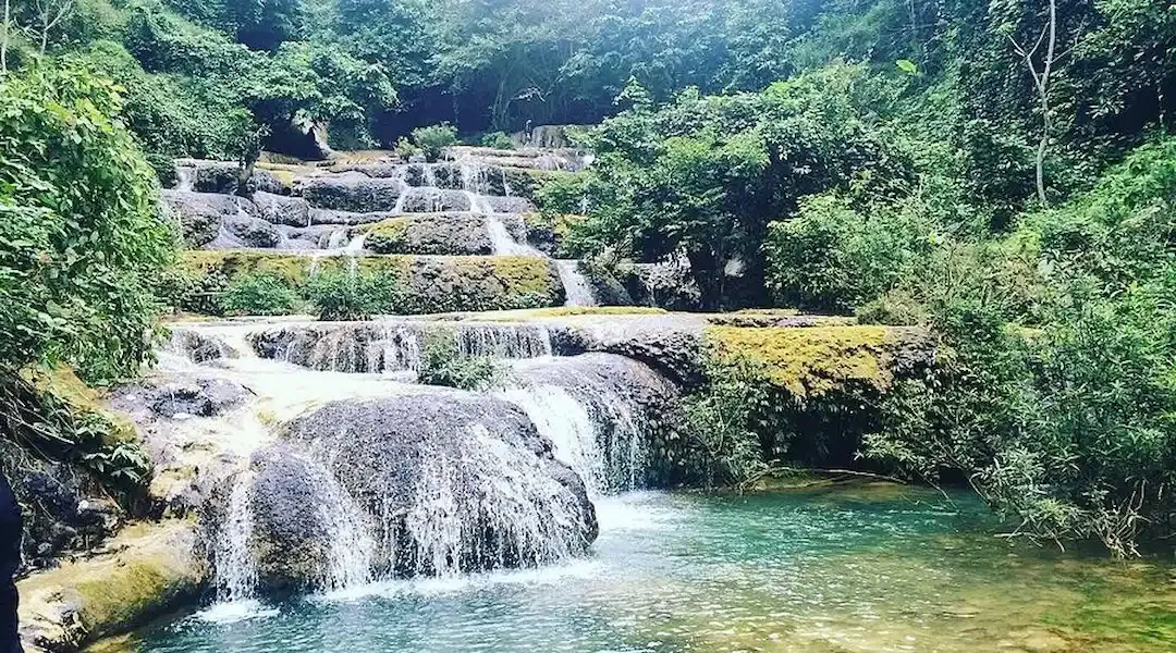Multi-tiered Hieu waterfall at Pu Luong Nature Reserve with turquoise pools and moss-covered limestone rocks surrounded by lush jungle forest, Vietnam
