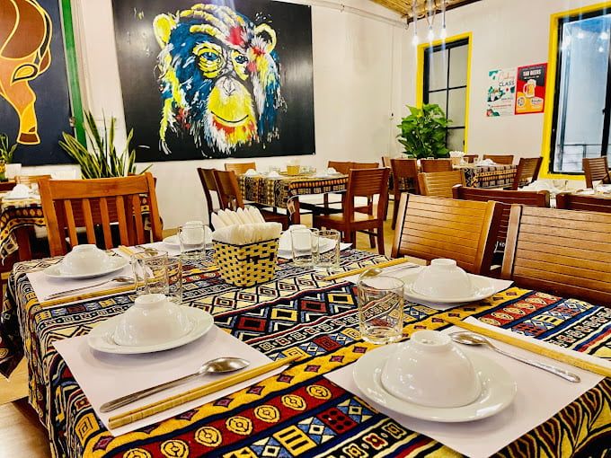 Cozy Vietnamese Restaurant Interior With Colorful Tablecloths, Wooden Chairs, and a Vibrant Mural of a Bear on the Wall