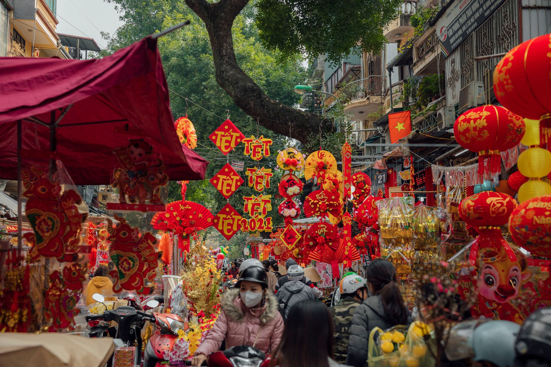 Crowded Vietnamese station concourse with Tet decorations and travellers carrying luggage