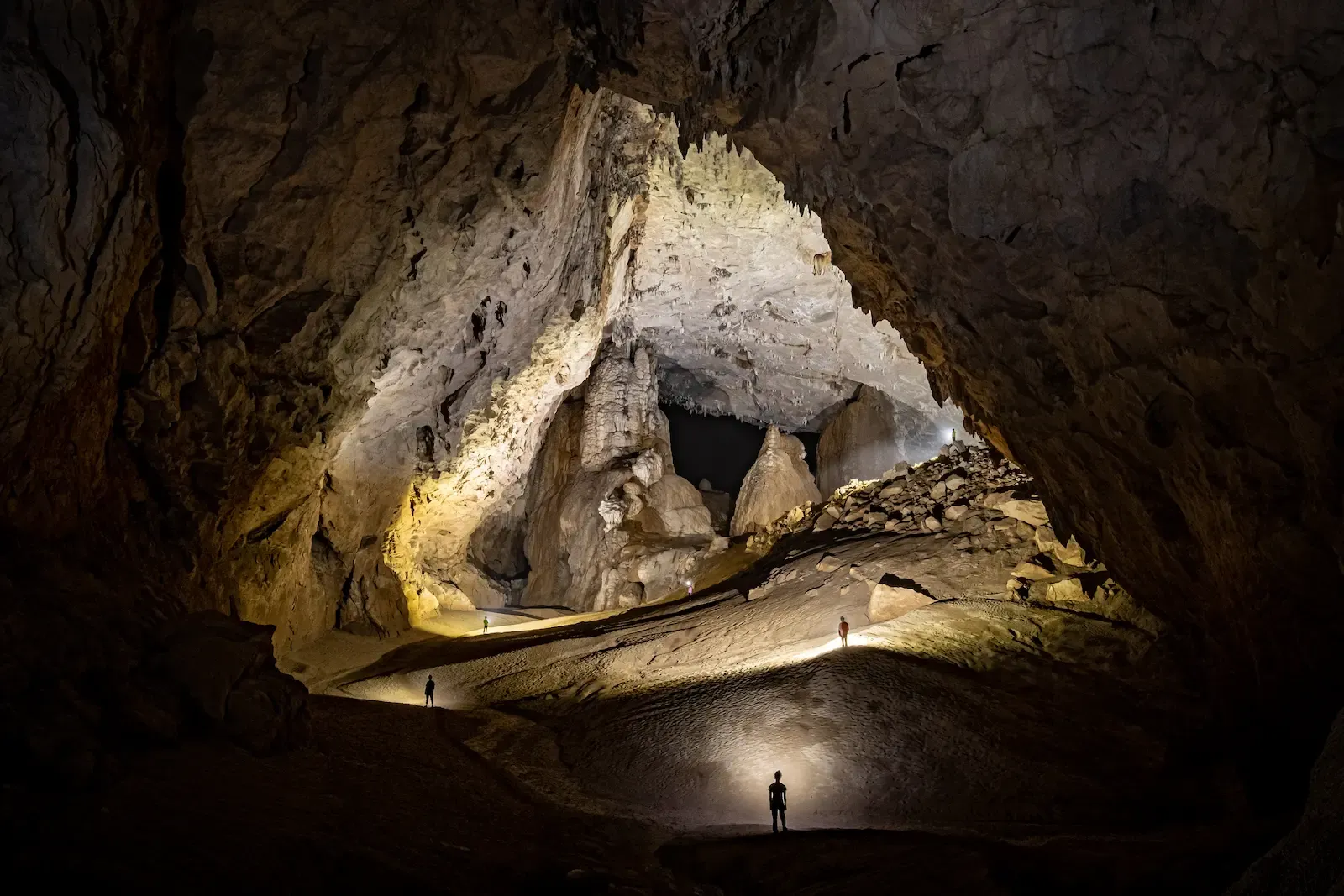 Expedition team navigating the massive chambers of Son Doong Cave in Vietnam, heading toward the Great Wall of Vietnam landmark.