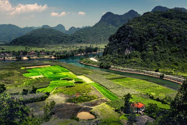 5. a Scenic View of Lush Green Fields and Mountains Surrounding a River Near Phong Nha Town.