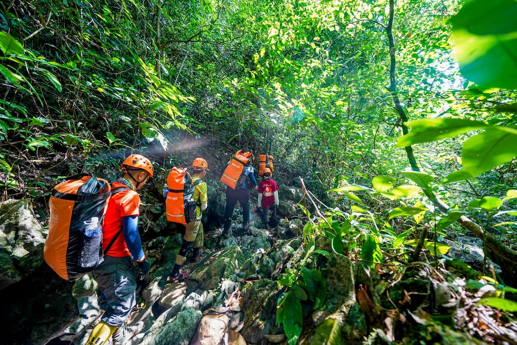 Trekkers in life jackets on a wet jungle trail in Phong Nha