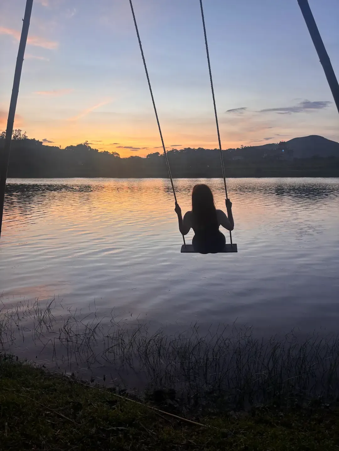 Woman on rope swing at sunset overlooking Son River at Phong Nha Funky Beach Vietnam