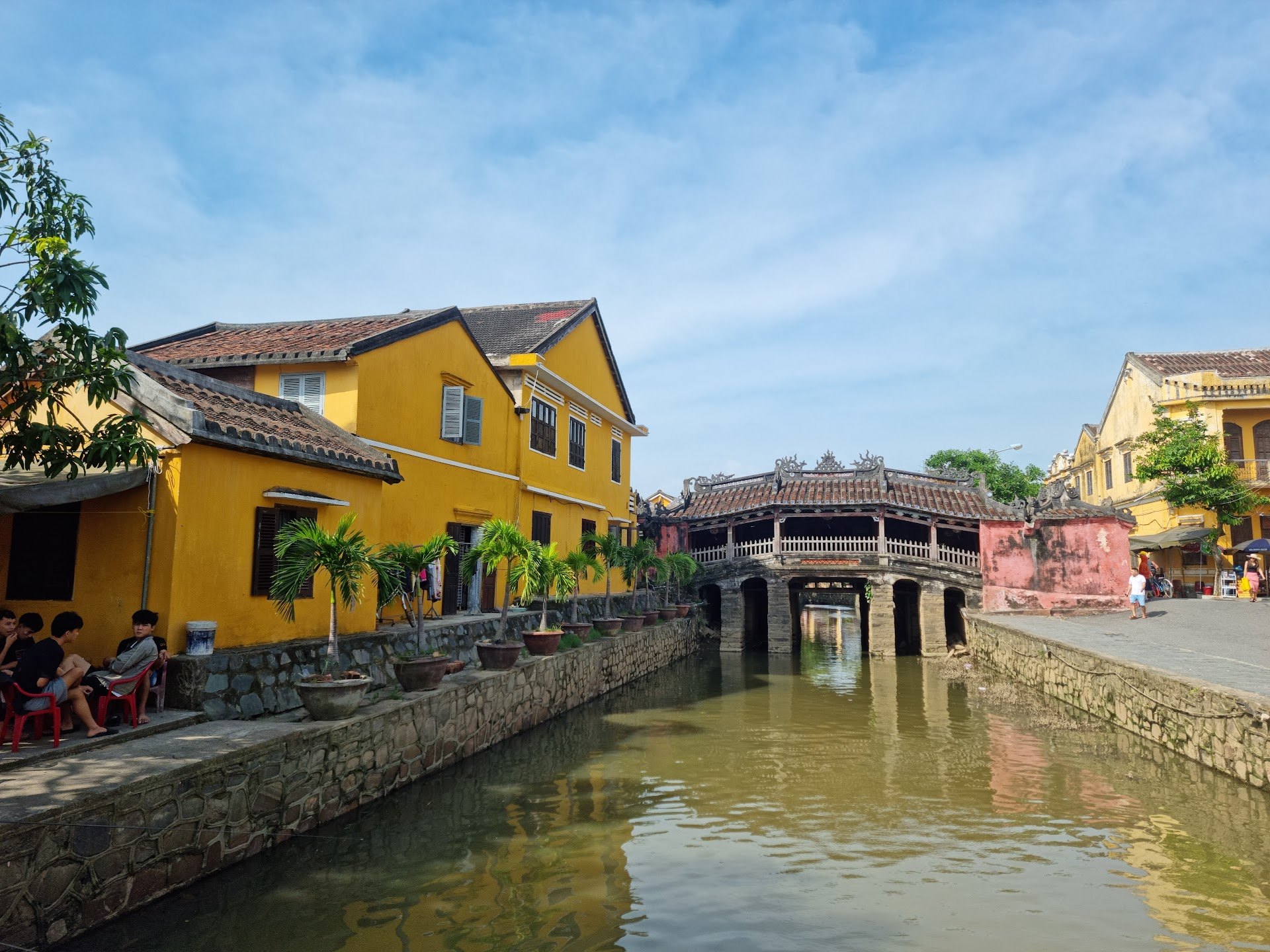 Japanese Covered Bridge and yellow houses beside a canal in Hoi An on a clear day