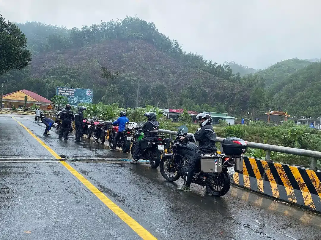 A group of bikers standing in rain during their group ride towards Halong Bay of Vietnam