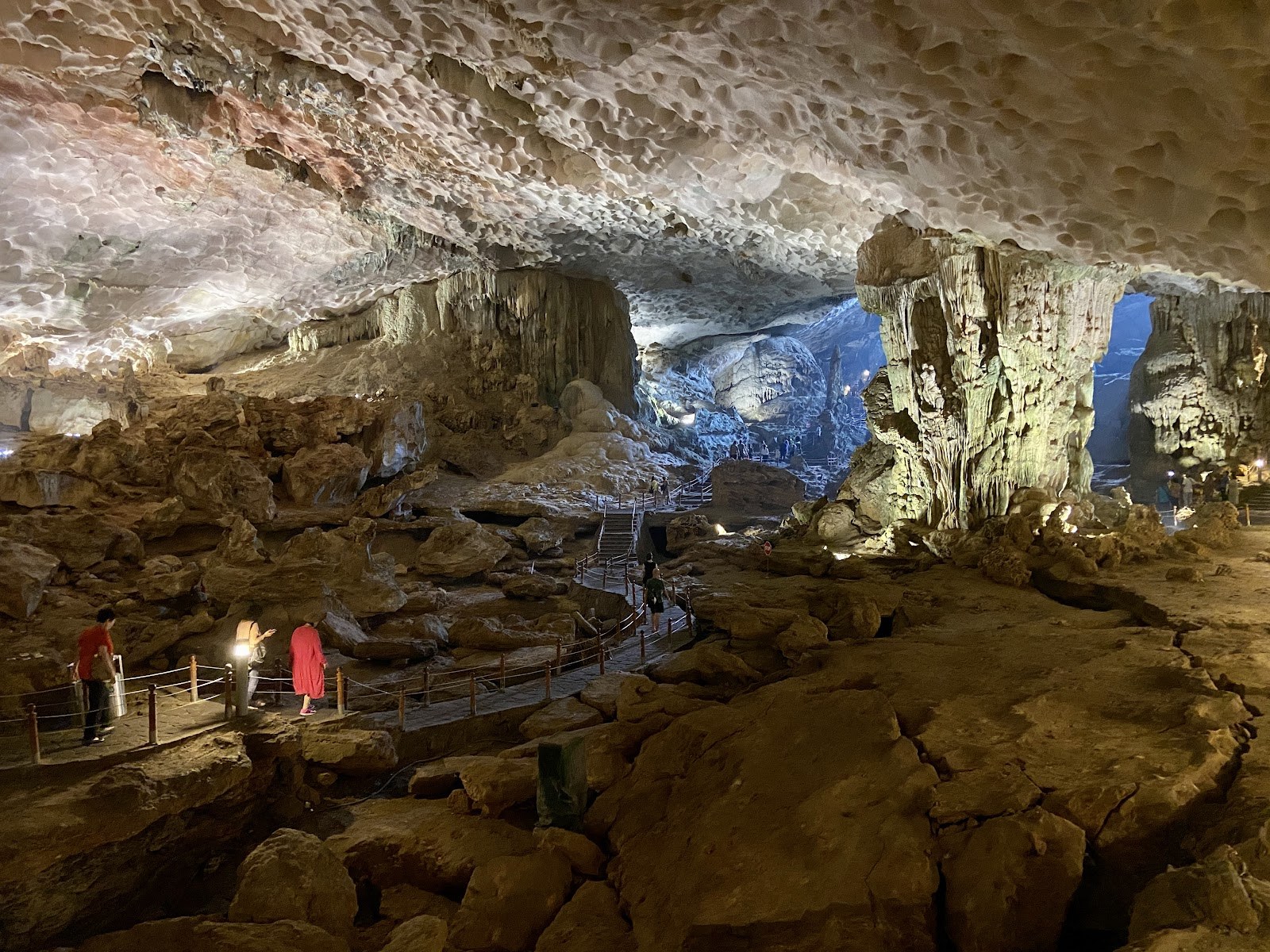 Visitors filing along the walkway inside a lit show cave in Ha Long Bay