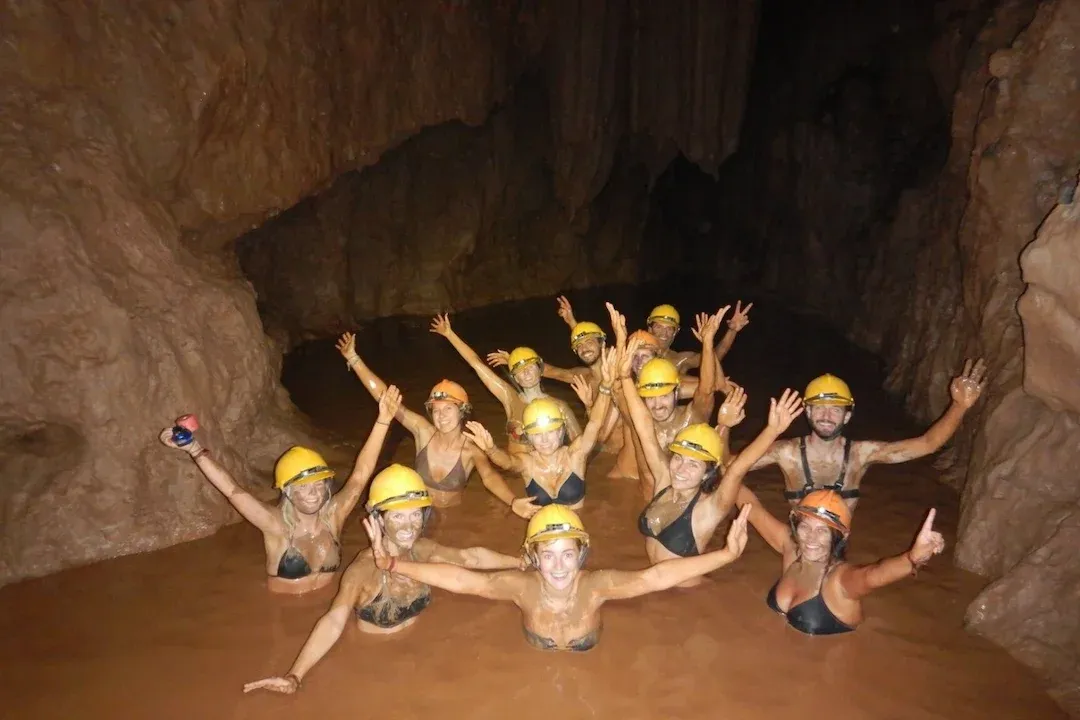 Group of travelers floating in natural mud bath inside Dark Cave at Phong Nha Vietnam