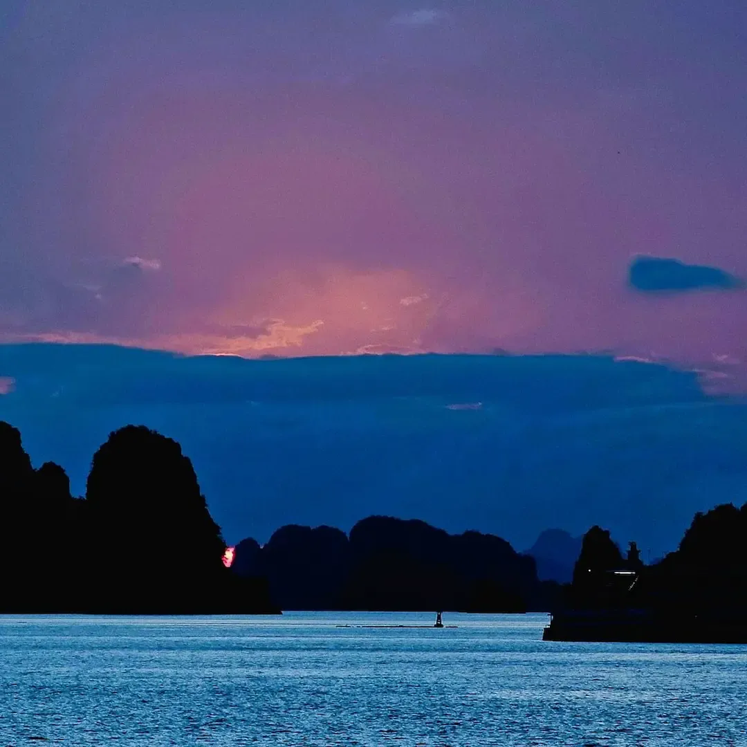 Dramatic Bai Tu Long Bay Sunset With Purple and Pink Sky Silhouetting Limestone Island Formations and Calm Turquoise Water   Peaceful Evening Atmosphere