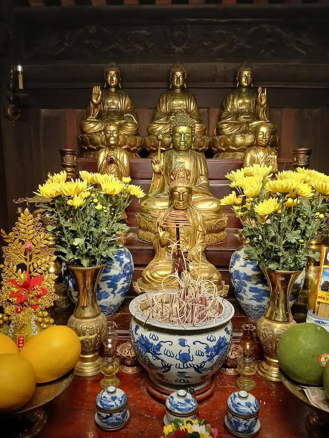 Hoa Lu Temple Interior Shrine With Golden Buddha Statues Bronze Arhat Sculptures Yellow Chrysanthemum Flowers Ceremonial Offerings Traditional Vietnamese Buddhist Worship Sacred Space