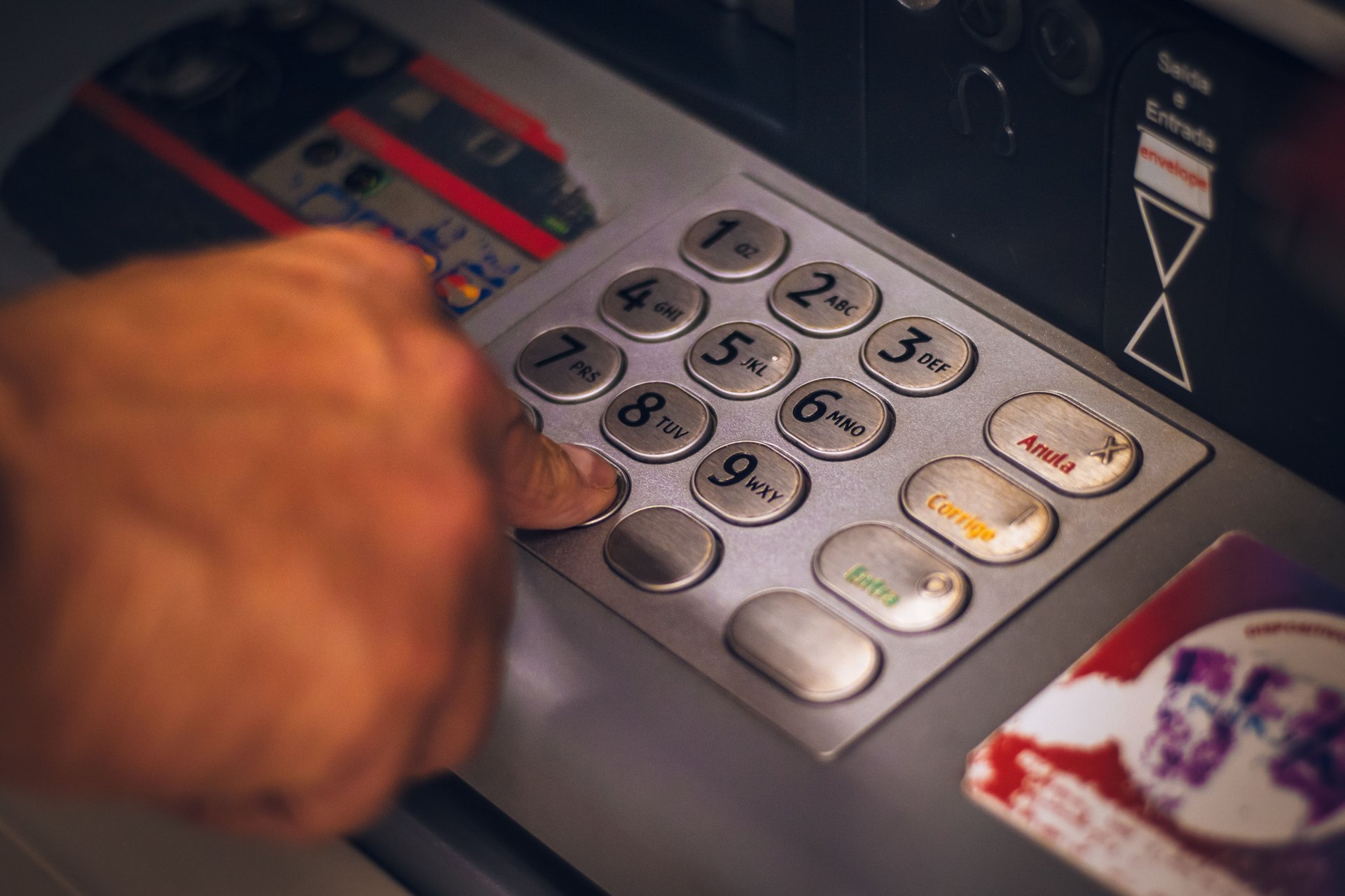 Hand entering a PIN on a cash machine keypad