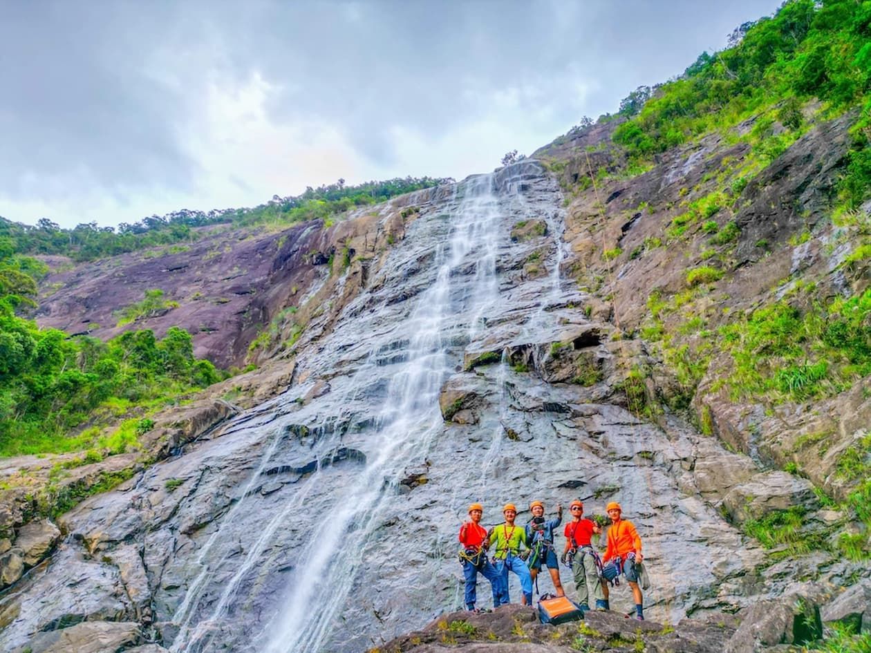 a Group of Trekkers Posing for Photographs With Do Quyen Waterfall in Full Flow in Background