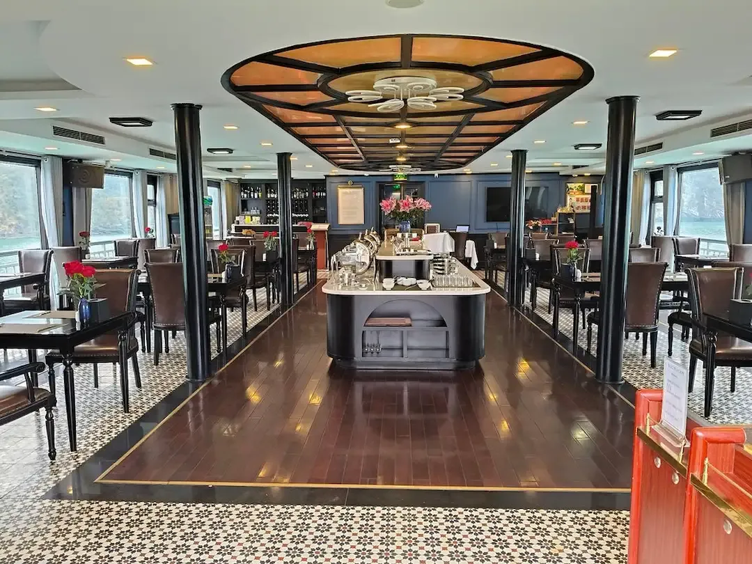 An Elegant Restaurant Dining Area Inside a Luxury Cruise With Floor to Ceiling Windows Overlooking the Bay, Featuring Modern Furnishings and an Upscale Ambiance.
