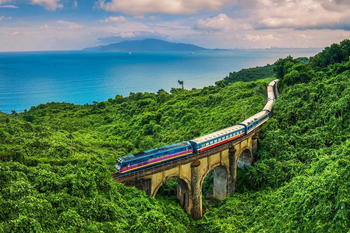 4. a Scenic Train Crossing a Bridge Surrounded by Lush Green Hills and Overlooking the Ocean While Travelling From Phong Nha to Hoi An